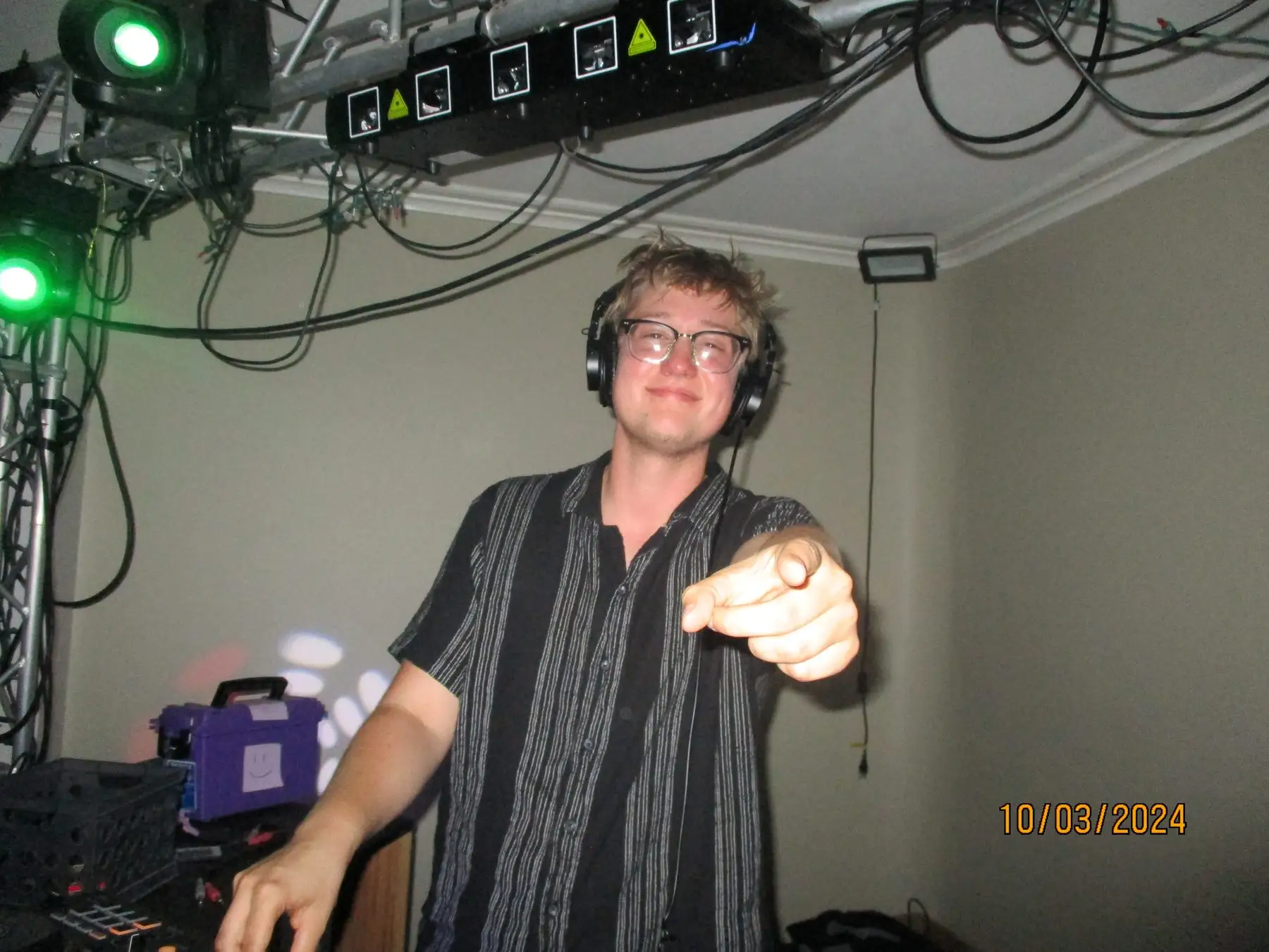 A brother DJing with headphones on, pointing at the camera