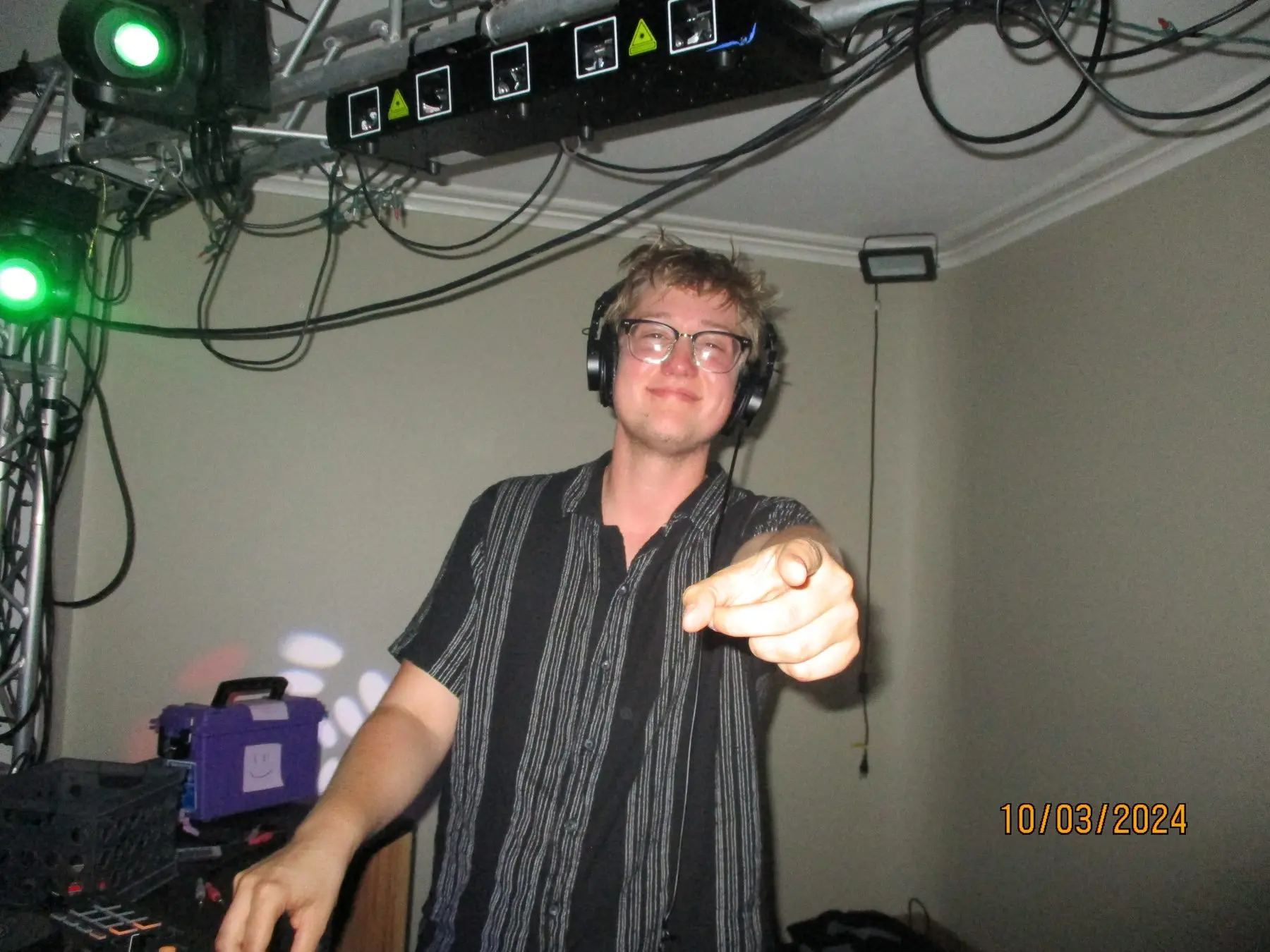 A brother DJing with headphones on, pointing at the camera
