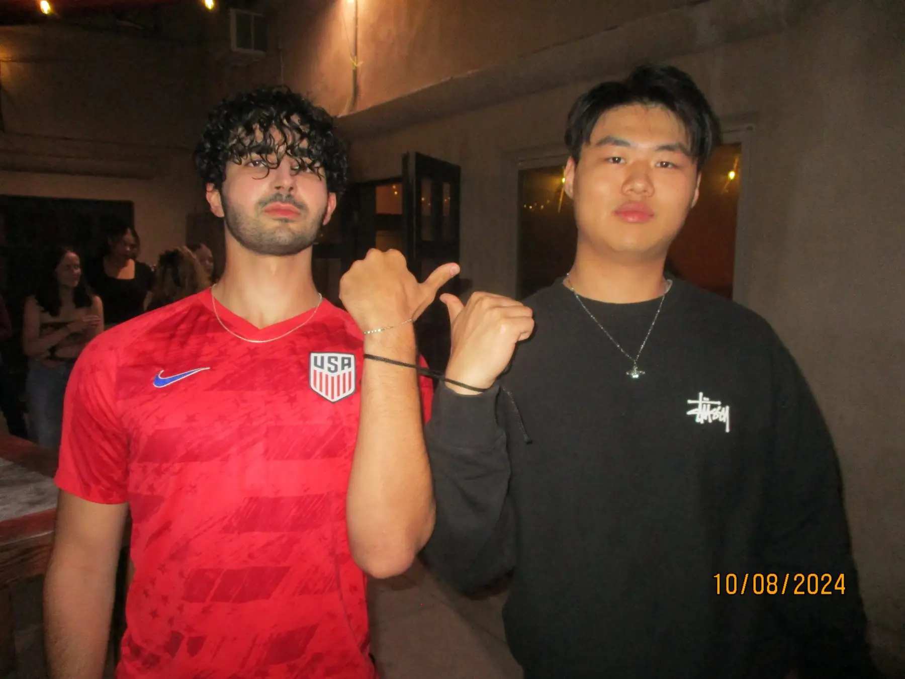 Two brothers showing matching bracelets at a night event
