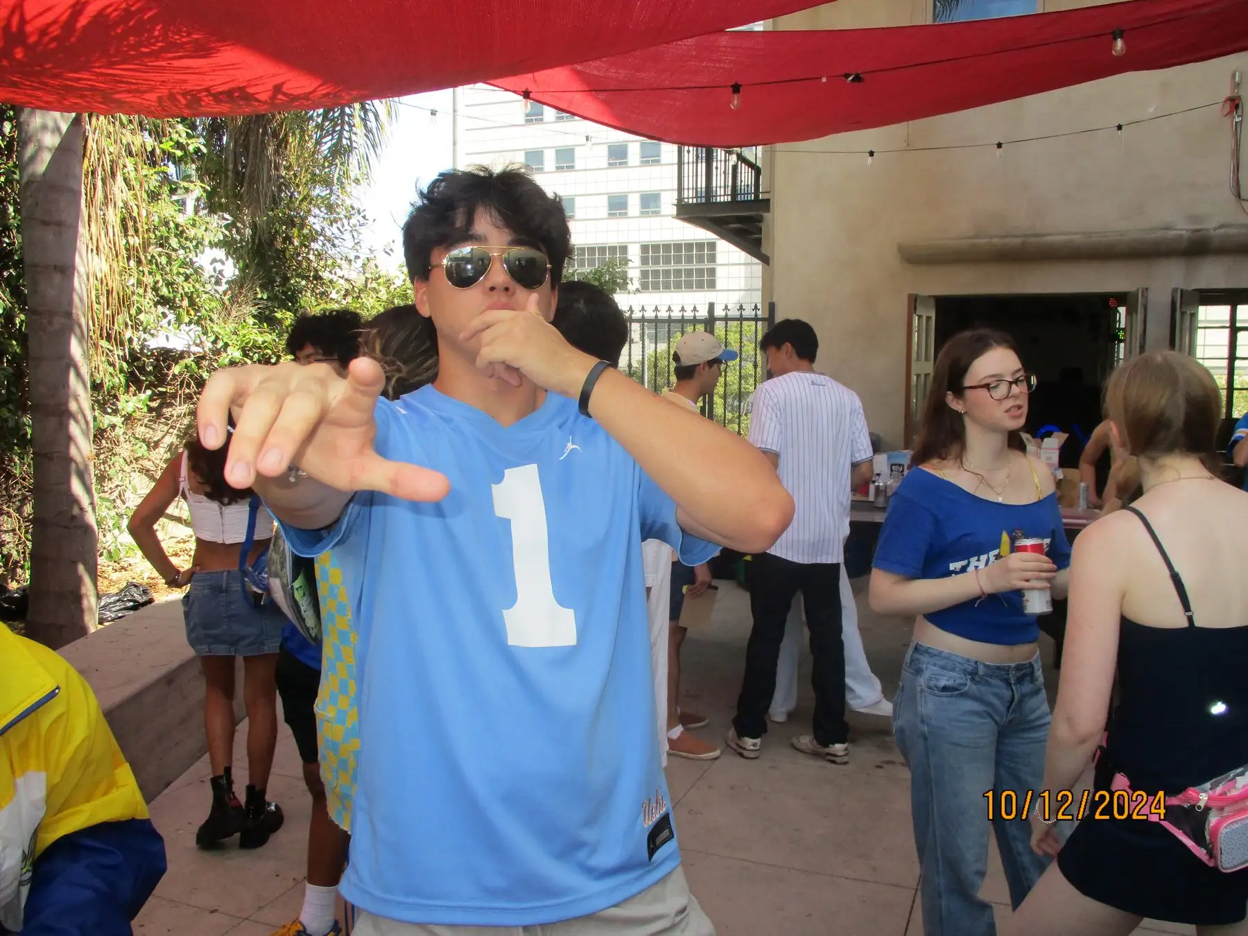 A brother in a UCLA number one jersey gesturing at the gameday party