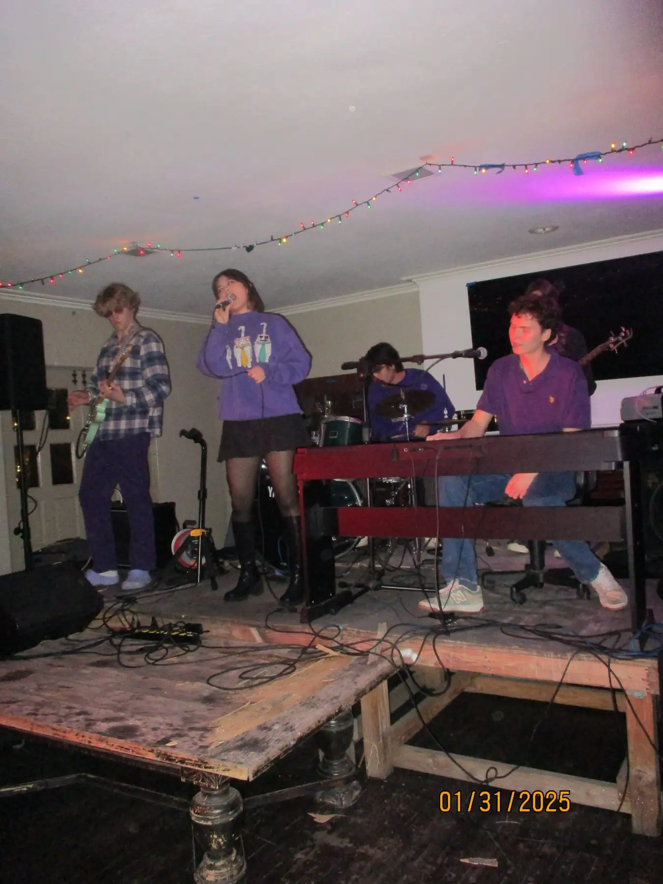 The house band with a guest singer playing under purple light