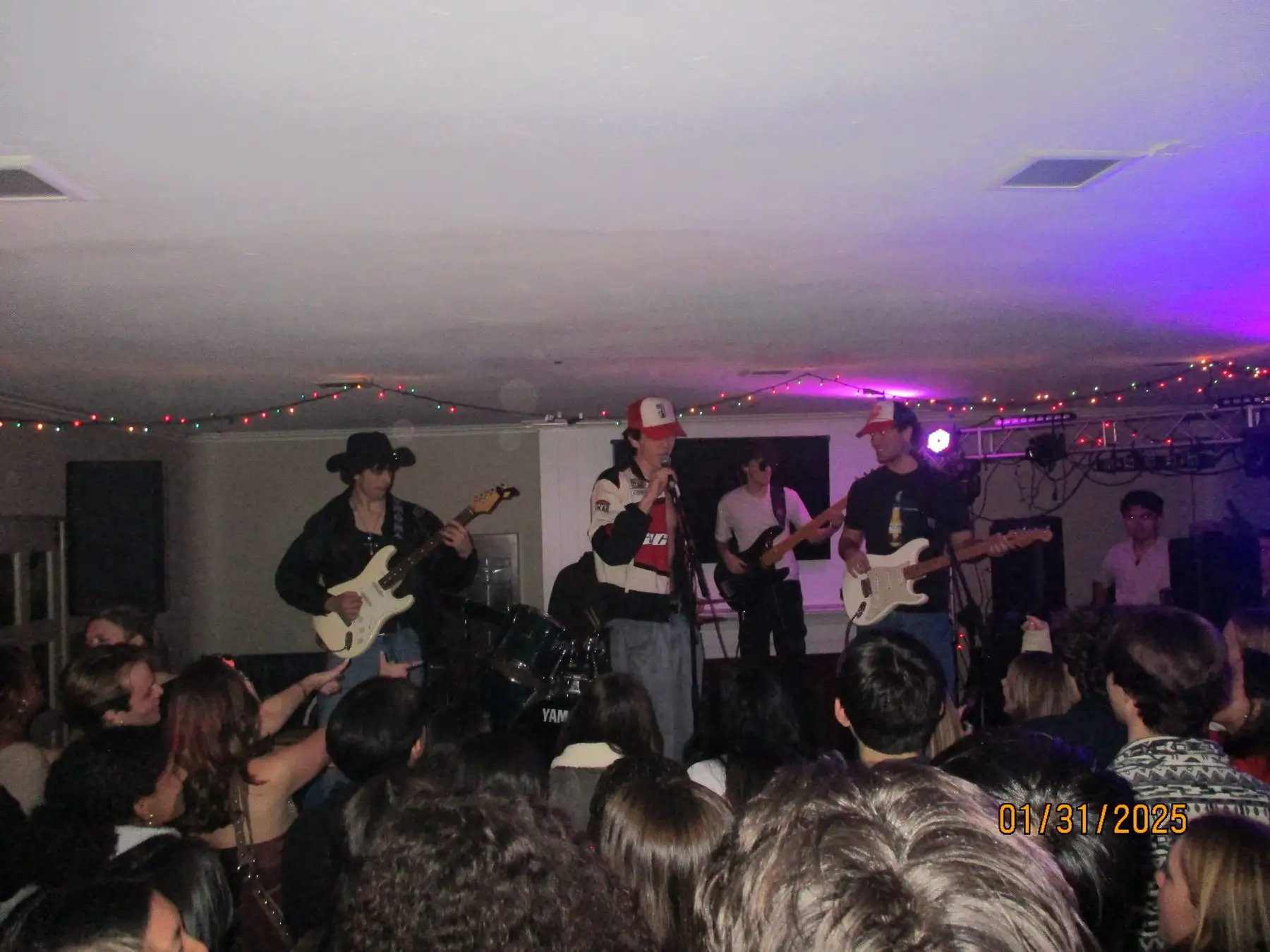 The band in cowboy hats playing to a packed living room