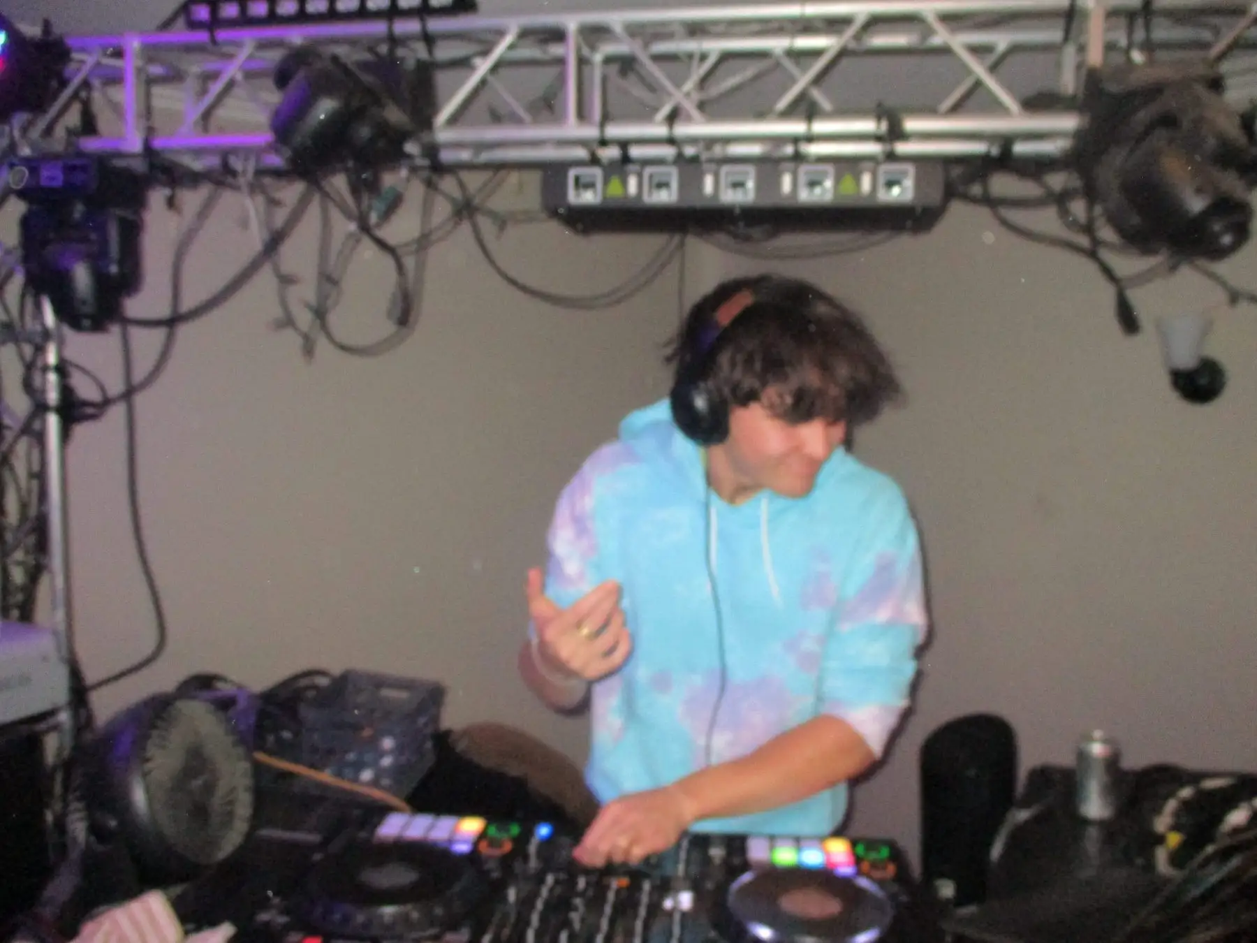 A brother in a tie-dye hoodie DJing under the light rig