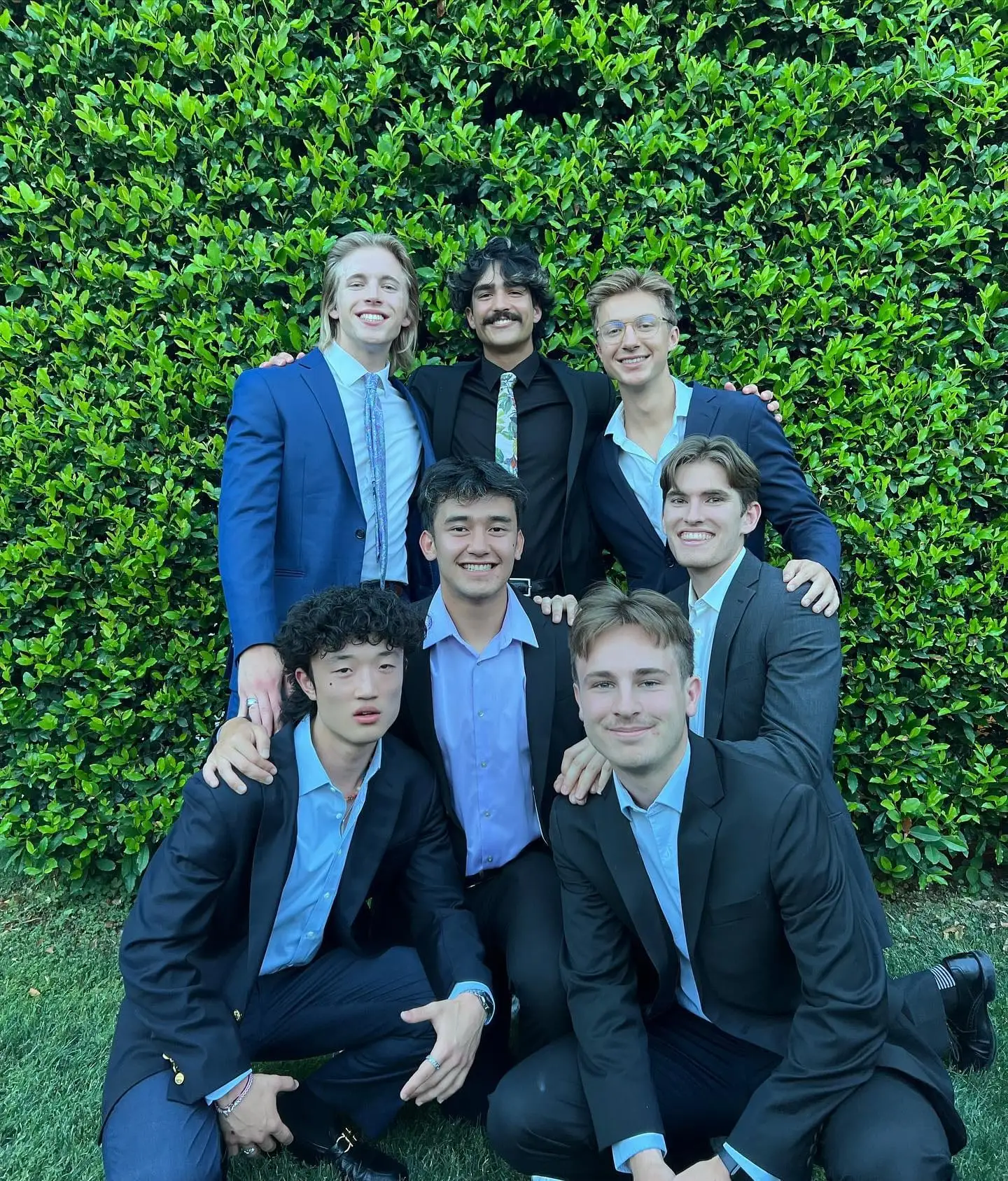 suits group posed against hedge